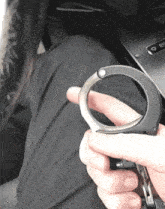 a person is holding a pair of handcuffs between their fingers