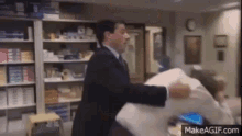 a man in a suit and tie is holding a pillow in a store .