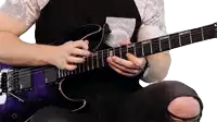 a man is playing a purple electric guitar with a black shirt and ripped jeans