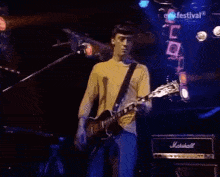 a man is singing into a microphone while another man plays a guitar on a stage .