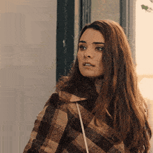 a woman wearing a plaid jacket looks to the side