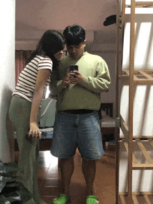 a man and a woman taking a picture of themselves in the mirror