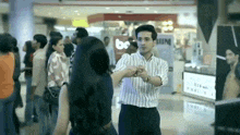 a man in a striped shirt is dancing with a woman in a mall