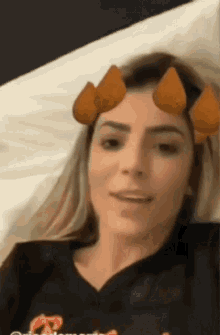 a woman wearing a black shirt with a t on it is laying in bed