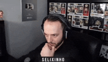 a man wearing headphones is sitting in front of a wall full of funko pop figures .