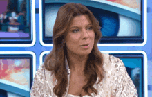 a woman with long brown hair is sitting in front of a wall of televisions