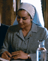 a woman in a nun 's veil sits at a table