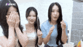 three girls are covering their faces with their hands and the word signal is above them