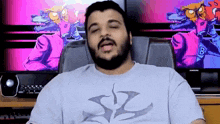 a man with a beard is sitting in a chair with his eyes closed in front of a computer screen .