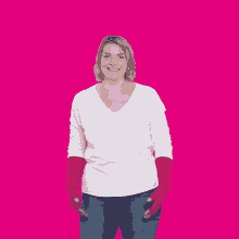 a woman in a white shirt and red gloves stands in front of a large pink heart