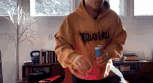 a man wearing a hoodie that says trash on it is holding a can of soda