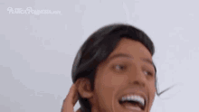 a man with a wig on his head is smiling and laughing .