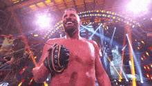 a man without a shirt is wearing a boxing glove and smiling at the camera