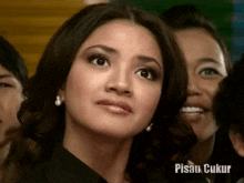 a woman with a black shirt and pearl earrings looks at the camera with the caption pisau ukur