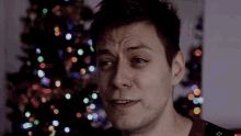 a close up of a man 's face with christmas lights in the background
