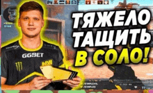 a man in a ggbet shirt is holding a wallet in front of a computer screen .