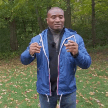a man wearing a blue jacket is standing in a park