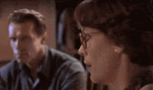 a man and a woman are sitting next to each other in a room and talking .