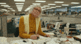 a woman in a yellow sweater is sitting at a desk