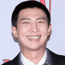 a man with a shaved head is smiling in front of a sign that has the letter v on it