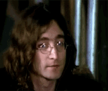 a close up of a man wearing glasses and long hair