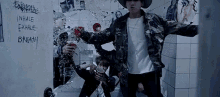 a group of young men are standing next to each other in a bathroom with a broken glass door .