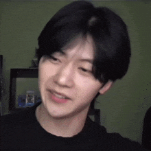 a young man with short black hair is making a funny face in a room .