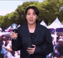 a man in a black jacket is holding a microphone and a balloon .