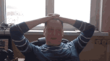 a man in a blue and white striped shirt holds his hands to his head