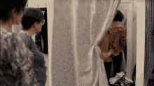 a woman is standing in a dressing room looking at herself in a mirror