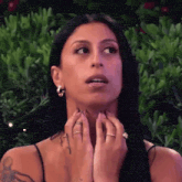a woman wearing earrings and a ring looks surprised