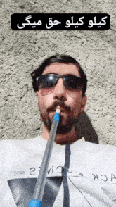 a man with a beard wearing sunglasses is smoking a pipe