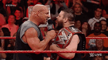 two wrestlers are talking to each other in a wrestling ring with a crowd watching .