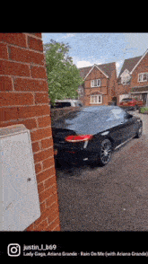 a black sports car is parked in front of a brick wall
