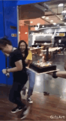 a man carrying a cake in a restaurant with a gifs art watermark on the bottom