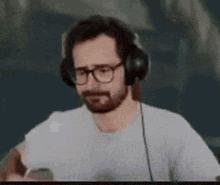 a man with a beard is wearing headphones and a white shirt .