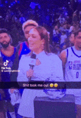 a woman is holding a microphone in front of a crowd and says shit took me out .