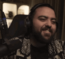 a man with a beard wearing headphones and a jacket that says e on it
