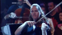 a woman is playing a violin in front of a bbc four sign