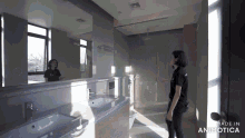 a woman in a black shirt is standing in a bathroom with the words made in animotica above her