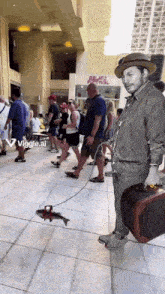 a man in a hat is walking a fish on a leash in front of a building that says gelato festival