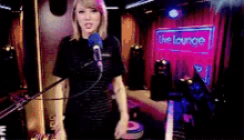 a woman is singing into a microphone in front of a live lounge sign