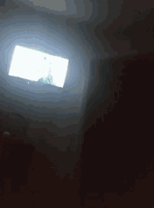 a television is turned on in a dark room with a light shining on it