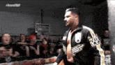 a wrestler in a black and yellow jacket with a crown on his chest