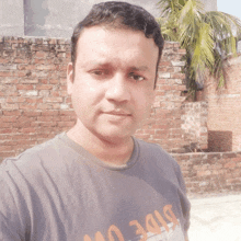 a man wearing a t-shirt that says side on it stands in front of a brick wall