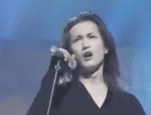 a woman is singing into a microphone on stage .