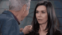 a man and a woman are looking at each other and the man is touching the woman 's face
