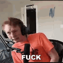 a man wearing headphones is sitting in front of a microphone saying fuck