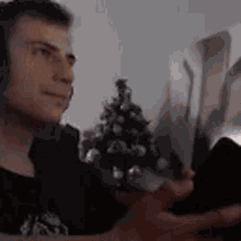 a man is sitting in front of a christmas tree and looking at a picture .