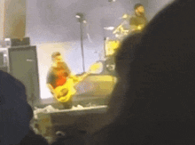 a blurry photo of a man playing a guitar on stage